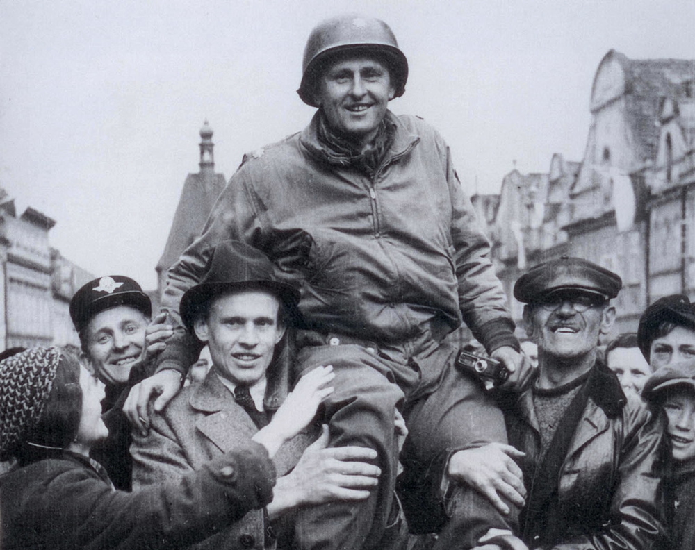 Matt Konop na ramenou obyvatel Domažlic 4. května 1945. Americká armáda právě osvobozuje české pohraničí. Foto: archív Patricka Dewana